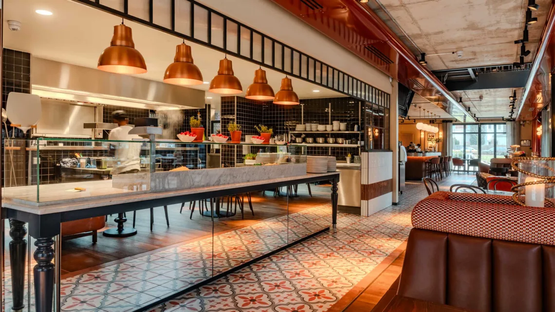 Restaurant mit offener Küche, Marmortheke und kupferfarbenen Pendelleuchten