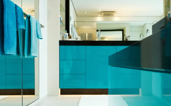 Badezimmer mit türkisfarbenen Waschtischunterschränken und großen Spiegeln